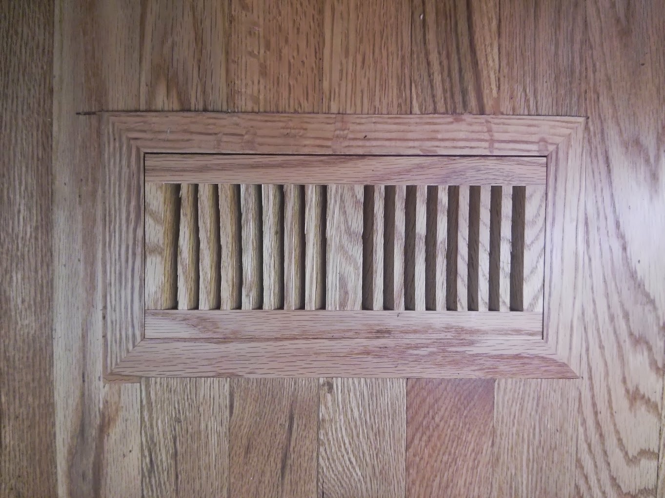 A new flush mount oak floor vent.  Cut and inlaid the floor vent into an existing hardwood floor.  Sanded flush with the floor and and finished.